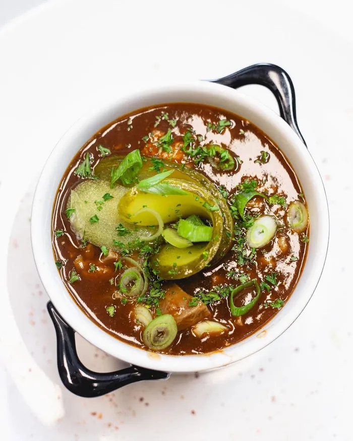 Plat mijoté servi en cocotte, légumes et herbes fraîches