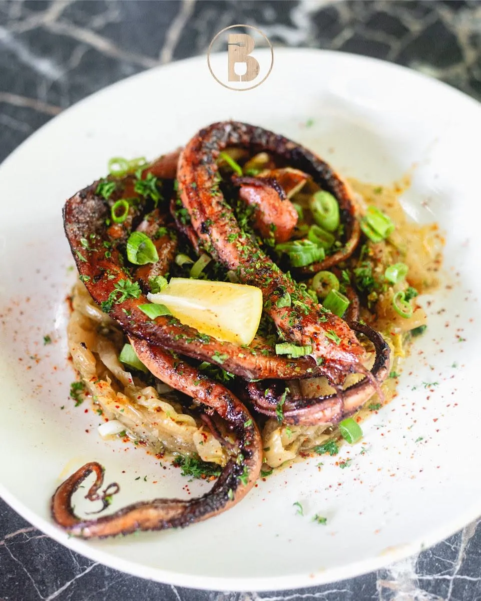 Tentacules de poulpe grillé, oignons nouveaux et quartier de citron