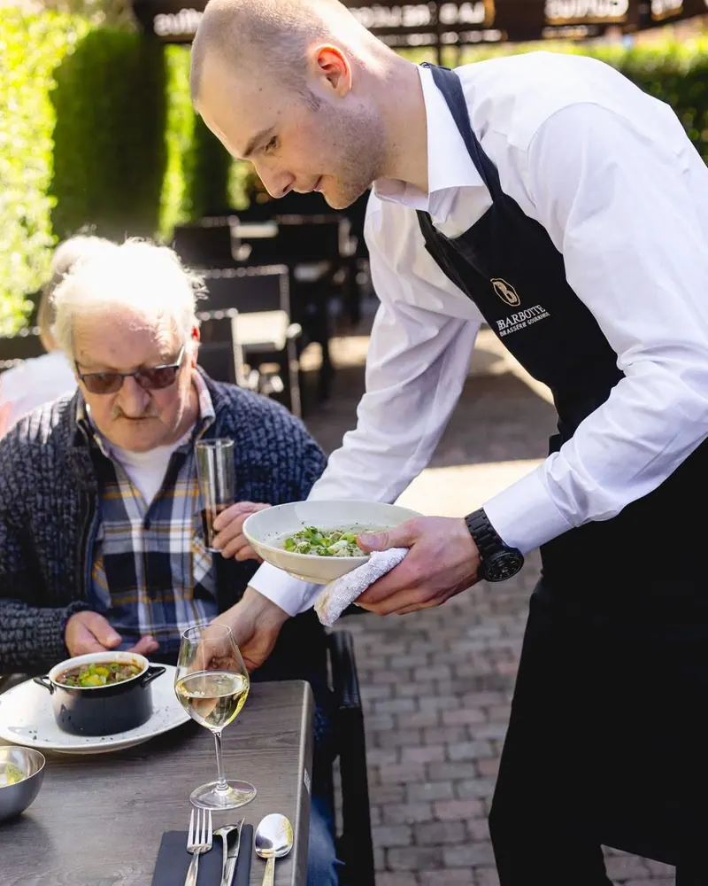 Un serveur dépose une assiette devant un client en terrasse