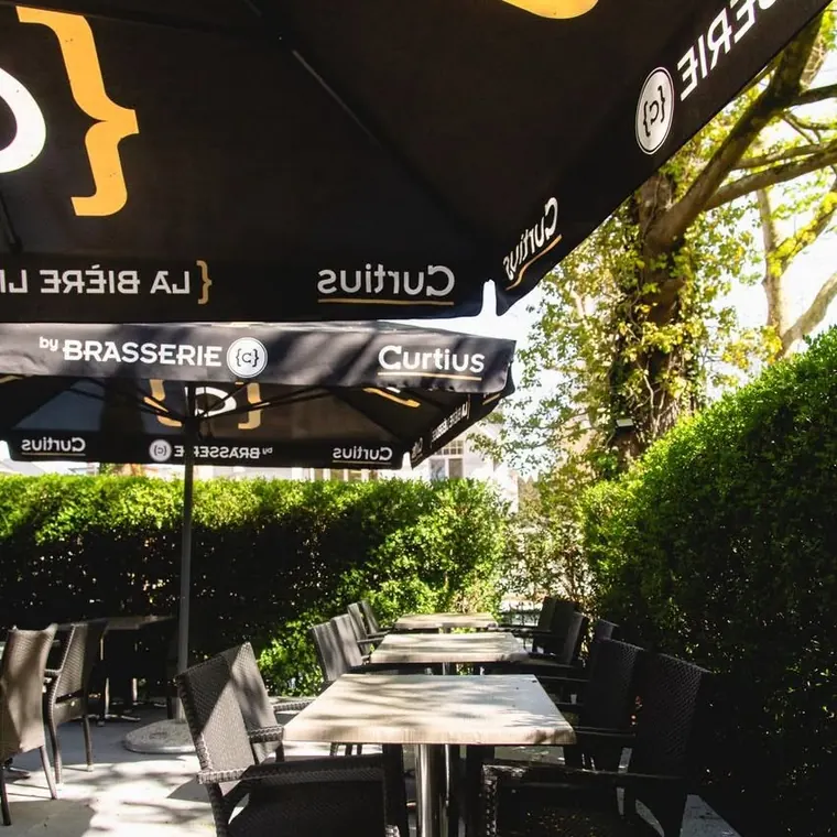 Terrasse bordée d’une haie taillée, tables dressées